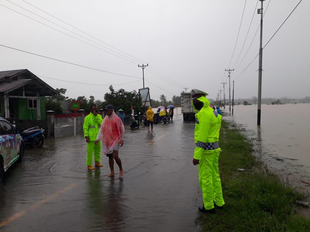 Diguyur Hujan, Polisi Tetap Semangat Atur Lalu Lintas di Lokasi Banjir