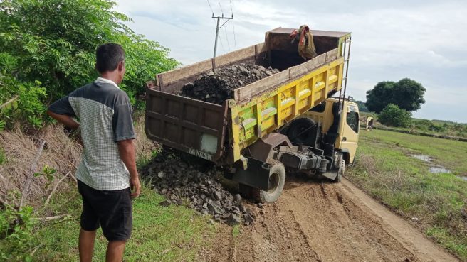Dump truk menurunkan material batu di jalan desa dalam kegiatan TMMD di Desa Temmabarang, Wajo.