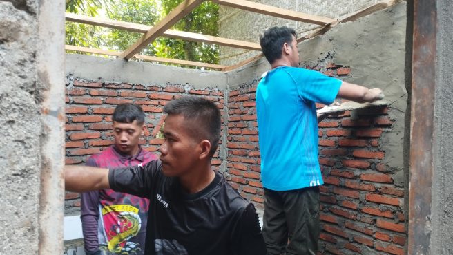 Anggota Satgas TMMD bersama warga Desa Temmabarang sedang mengerjakan pembangunan fasilitas MCK dengan cara memplester dinding bata merah di Kabupaten Wajo.