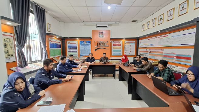Suasana rapat internal KPU Kabupaten Wajo yang dihadiri oleh sejumlah staf dan pejabat, berlangsung di ruang rapat utama kantor KPU dengan tampilan visual penuh informasi dan poster di dinding.
