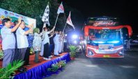 Dirjen PHI Jamsos Kemnaker Indah Anggoro Putri kibarkan bendera lepas bus mudik gratis di malam hari.