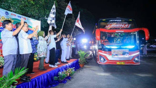Dirjen PHI Jamsos Kemnaker Indah Anggoro Putri kibarkan bendera lepas bus mudik gratis di malam hari.