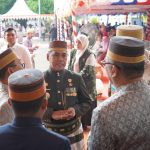 Bupati Wajo Andi Rosman mengenakan Jas Tutup hijau tua beradu argumen santai dengan pejabat lain di sela acara Hari Jadi Bone, mengenakan Songkok Recca dan sarung sutra Lipa Sabbe.